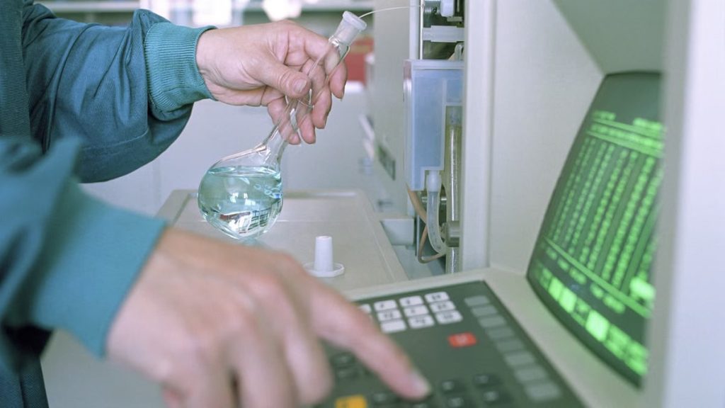 Close-up of a scientist operating lab equipment with a flask in hand.